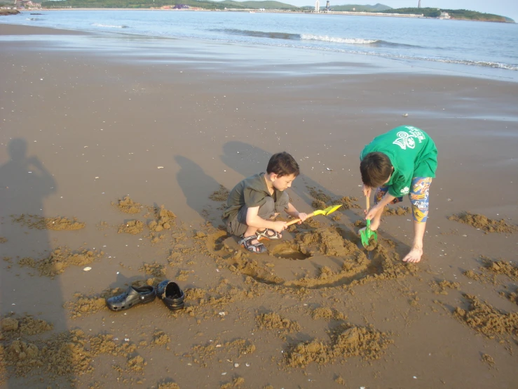 two children playing with sand and making a picture