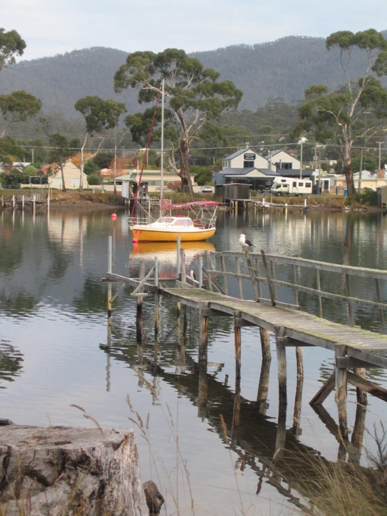 a boat docked in water next to a wooden bridge