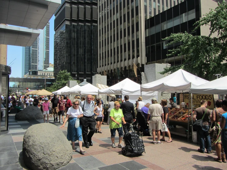 many people are standing around at an outdoor market