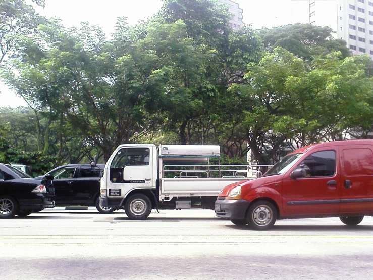 a white truck driving past two black vehicles