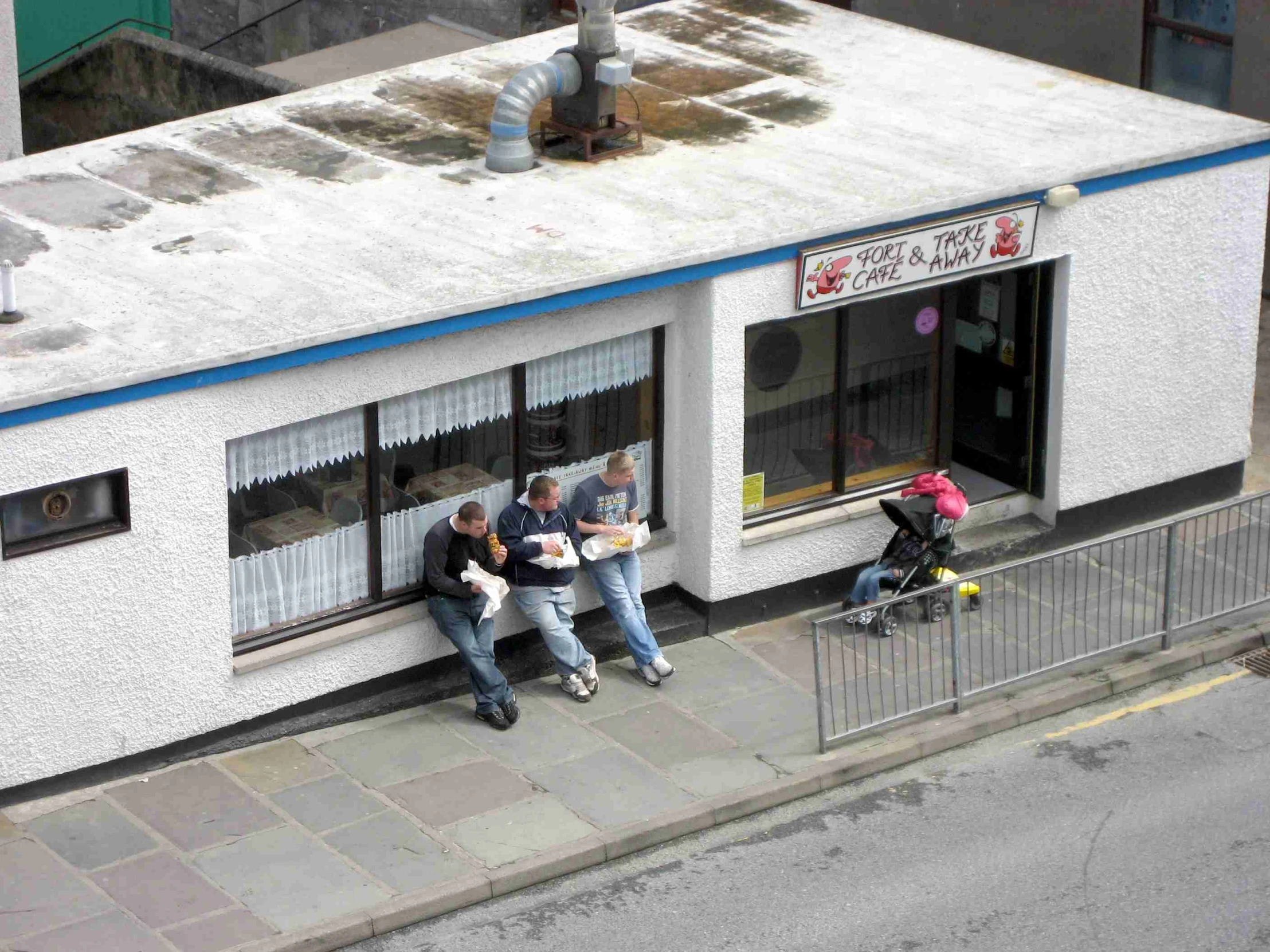 a couple eating food from a buffet in front of a building