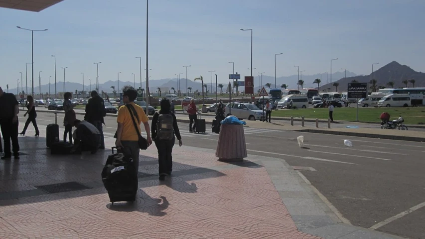 a group of people walk with their luggage across the street