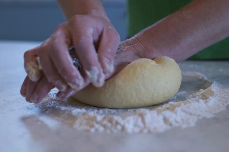 someone kneading together dough on a table