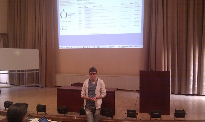 a man standing next to a chair in front of a projection screen