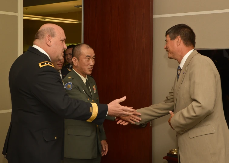 four military men in a room are having some conversation