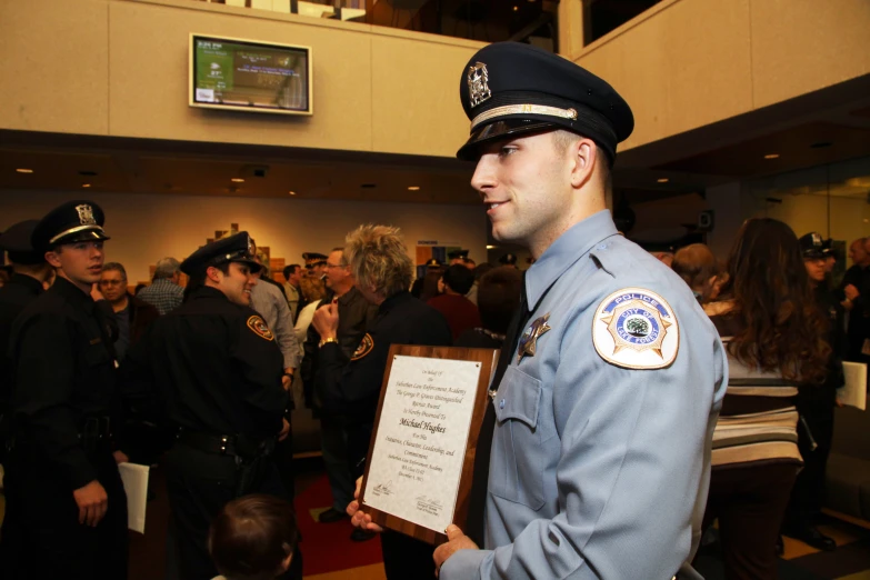 a cop holds an award plaque and talks to someone