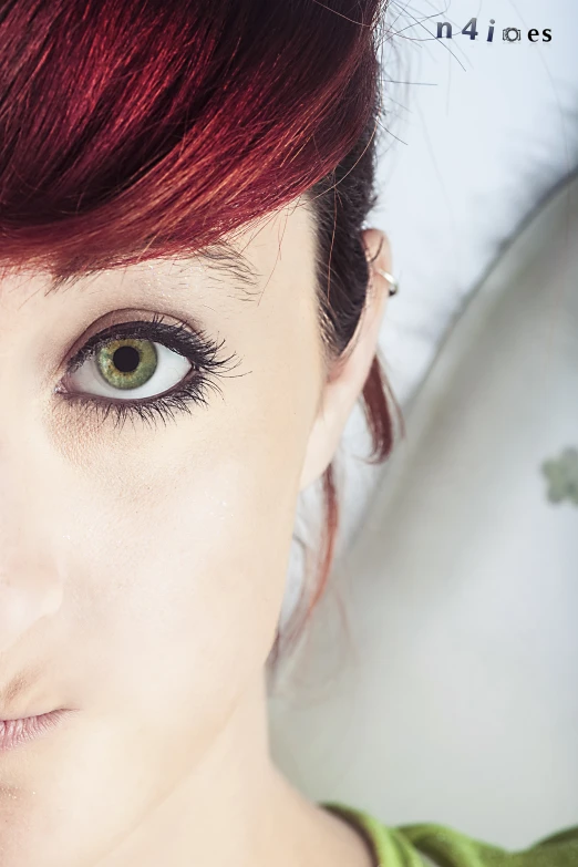 a woman with long red hair and green eyes wearing makeup