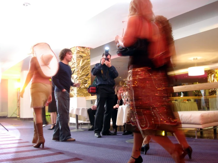 three people take pictures of a woman in a red dress and man in black suit