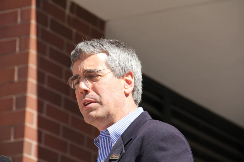 a man with grey hair speaking into a microphone