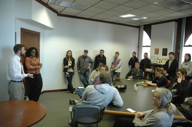 a group of people are standing in a meeting room