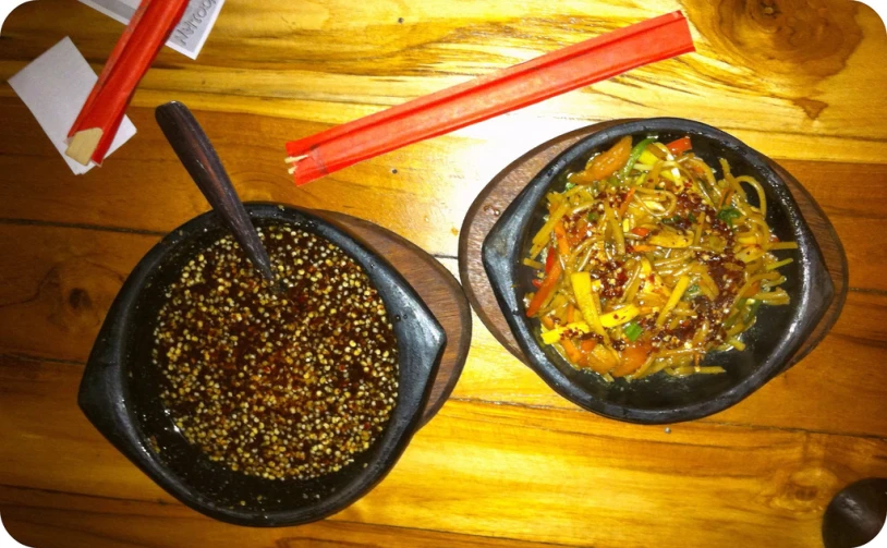 a wooden table top with two bowls of food on it