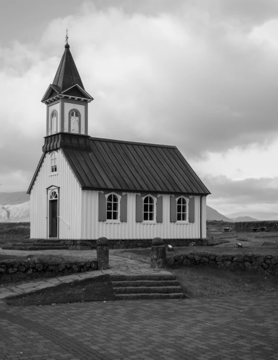 the small white building has a steeple and door