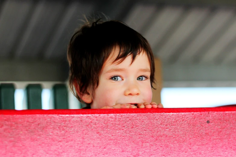 the child is peering from a high ceiling with a red wall