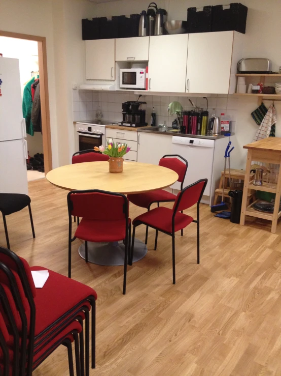 the empty kitchen has many red chairs in it