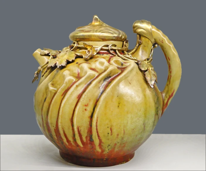 an old, carved yellow tea pot with red and gold designs