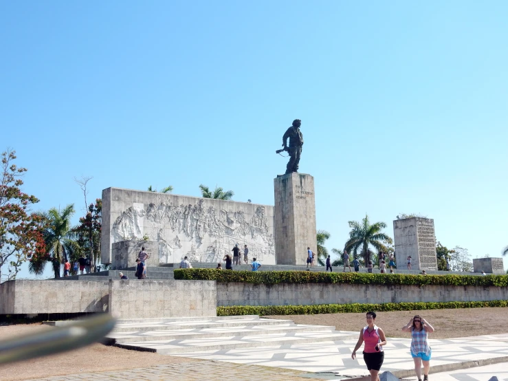 two girls are standing by a statue with a man on top