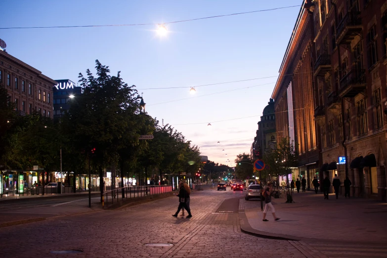 people walking on the street in an area with cobblestone pavement and buildings