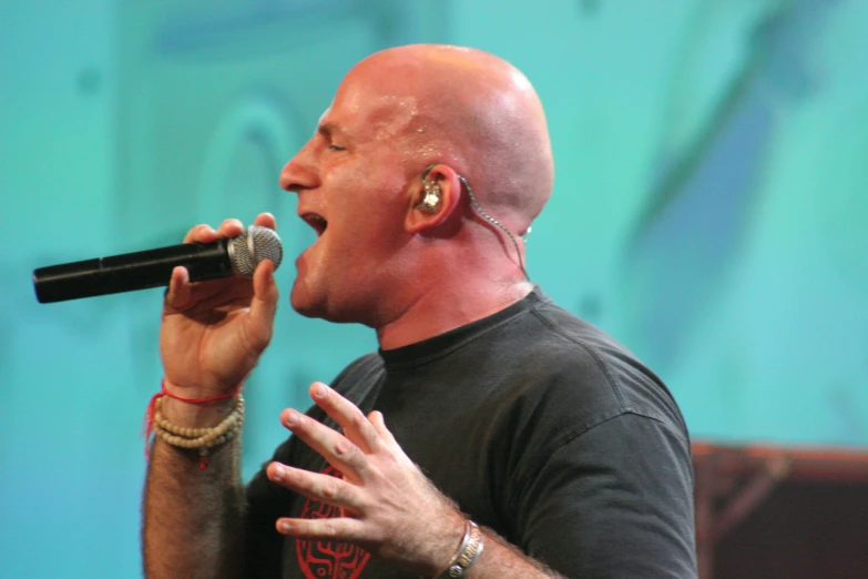 a bald man wearing head phones singing into a microphone