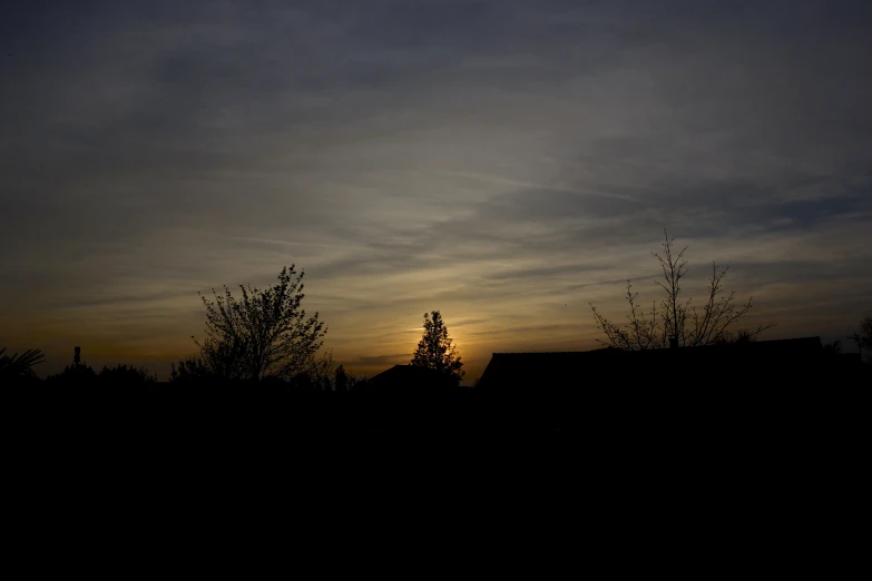 the sun sets behind some trees and buildings