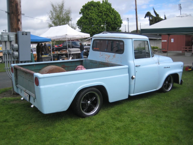 an old blue truck is parked in some grass