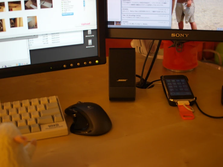 an iphone, computer monitor, mouse and speakers on a desk