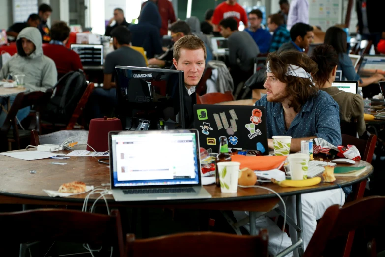 two people sit in front of laptop computers