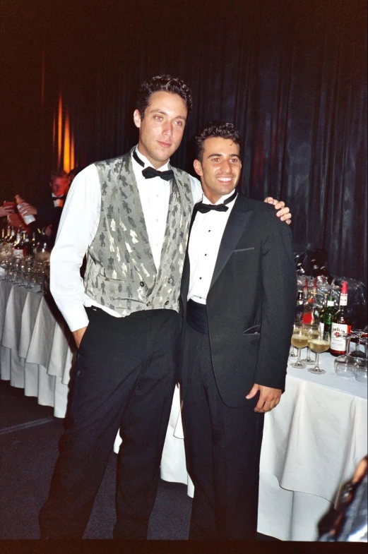 two men standing next to each other in formal clothes