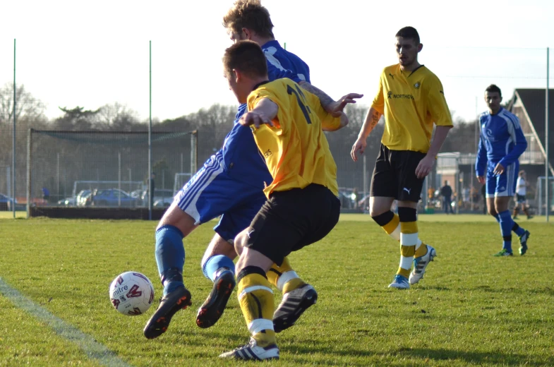 boys playing soccer on grass with two teams behind them