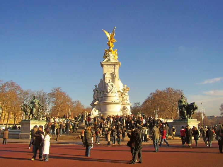 people are walking through the streets near a statue