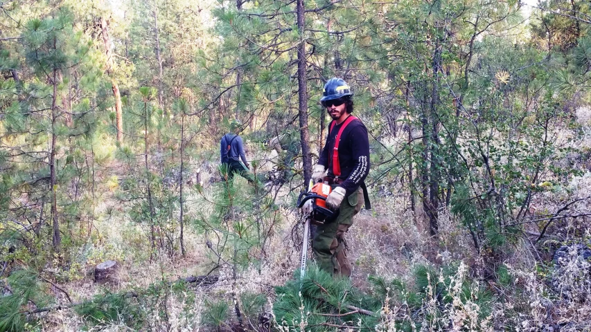 man carrying an animal in the woods on a trail