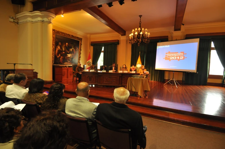 a group of people sitting on chairs around a table in front of a screen