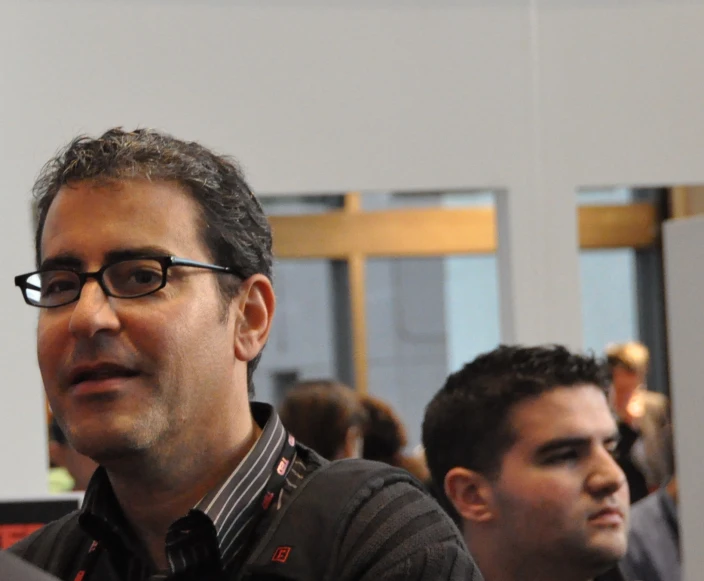 a man wearing eyeglasses sits in a line