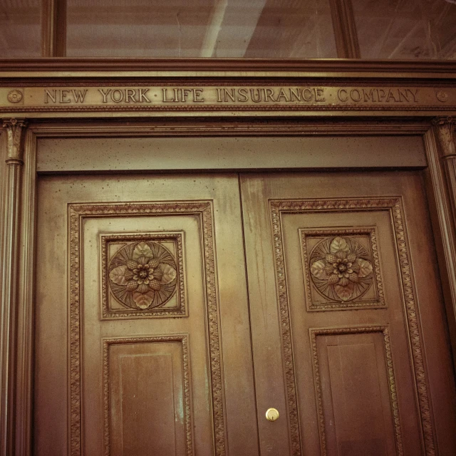 an ornate wood door with carved detailing and writing on the bottom