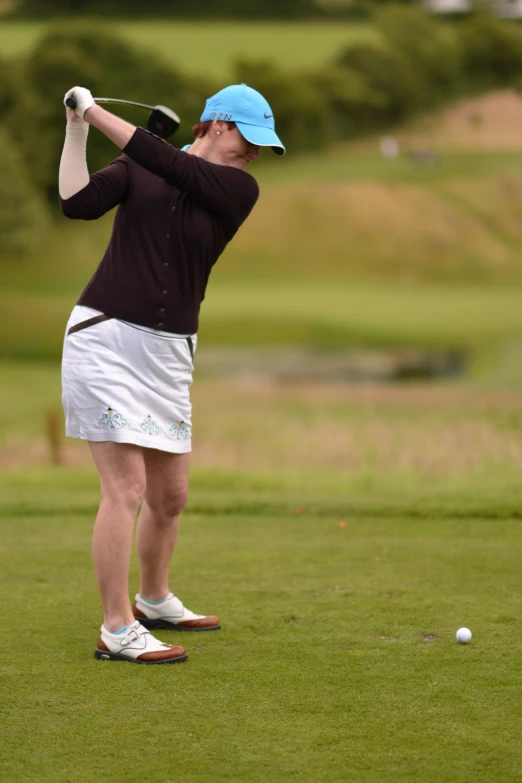 a woman in a blue hat is playing golf