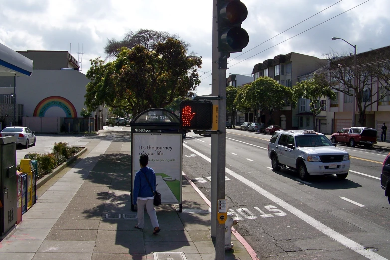 man standing at the crosswalk waiting at the red traffic signal