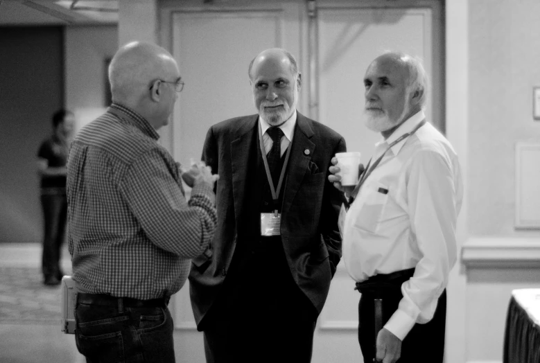 an older man with glasses stands with three other elderly men