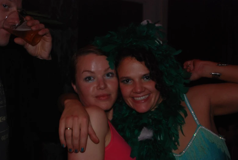 two women with green feathers and rings pose for the camera