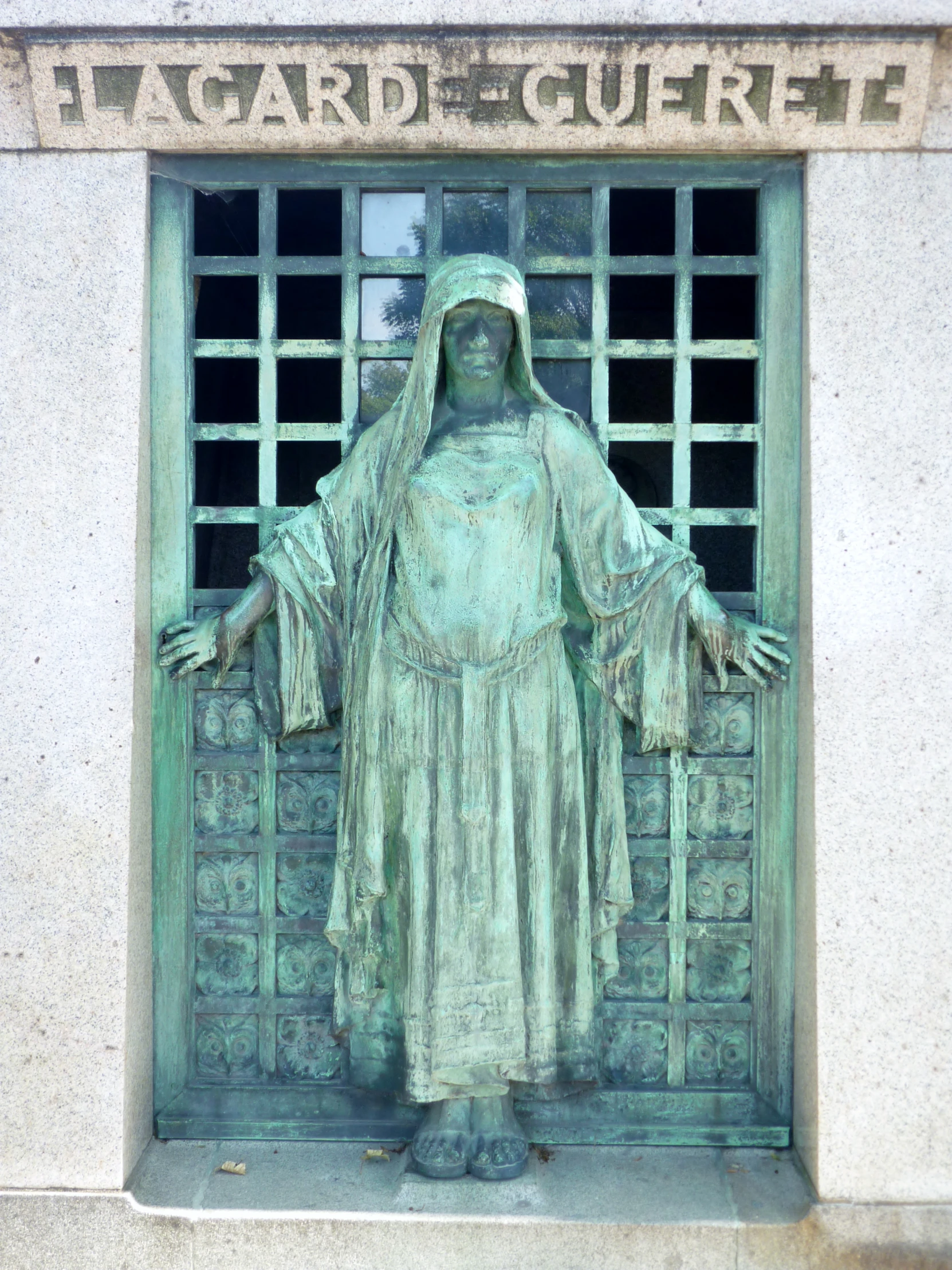 the statue has a long robe, long white hair and a cross over it