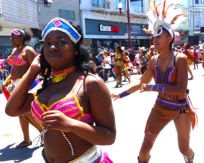 two women dressed in colorful costumes performing a dance on the street