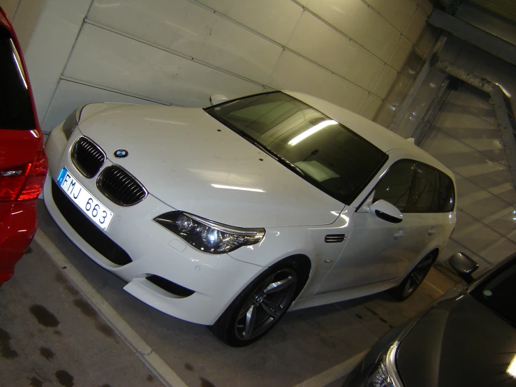 a white car in a parking garage next to a red car