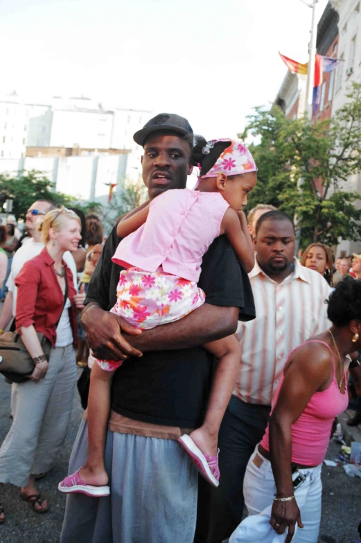 a man holding two children, at a street parade