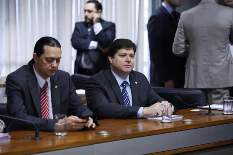 three men are sitting at a long table