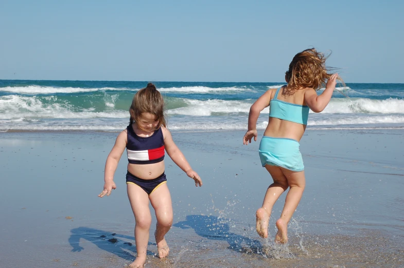 two little girls on the beach playing in the water