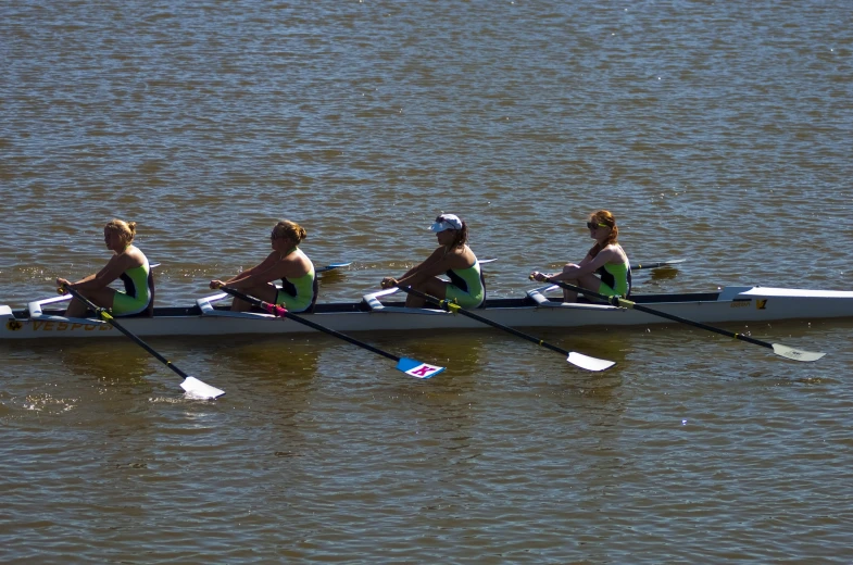 three women sit side by side on a long boat