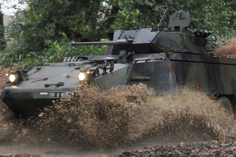 a couple of army vehicles driving through some dirt