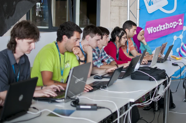 a bunch of people sitting in front of some laptops