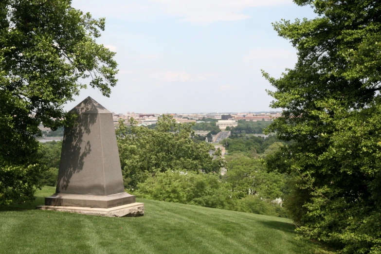 a monument in the middle of the field with trees in the background