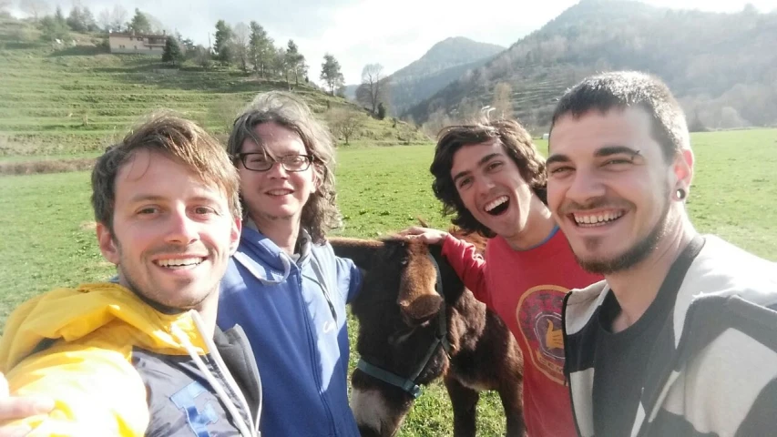 group of people standing in field next to a brown horse