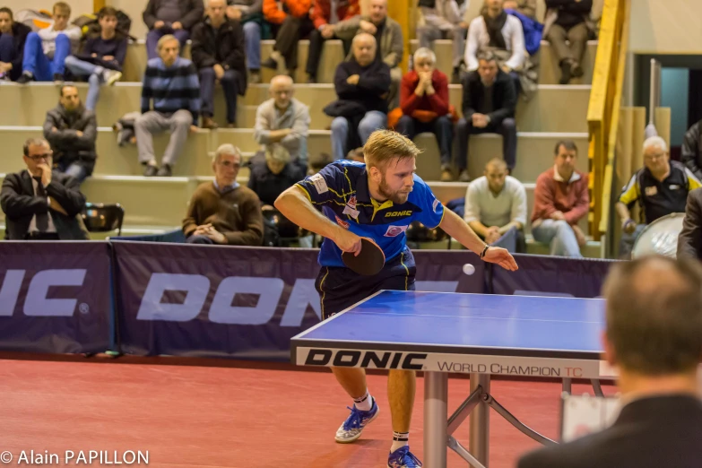 the table tennis player is serving for a crowd