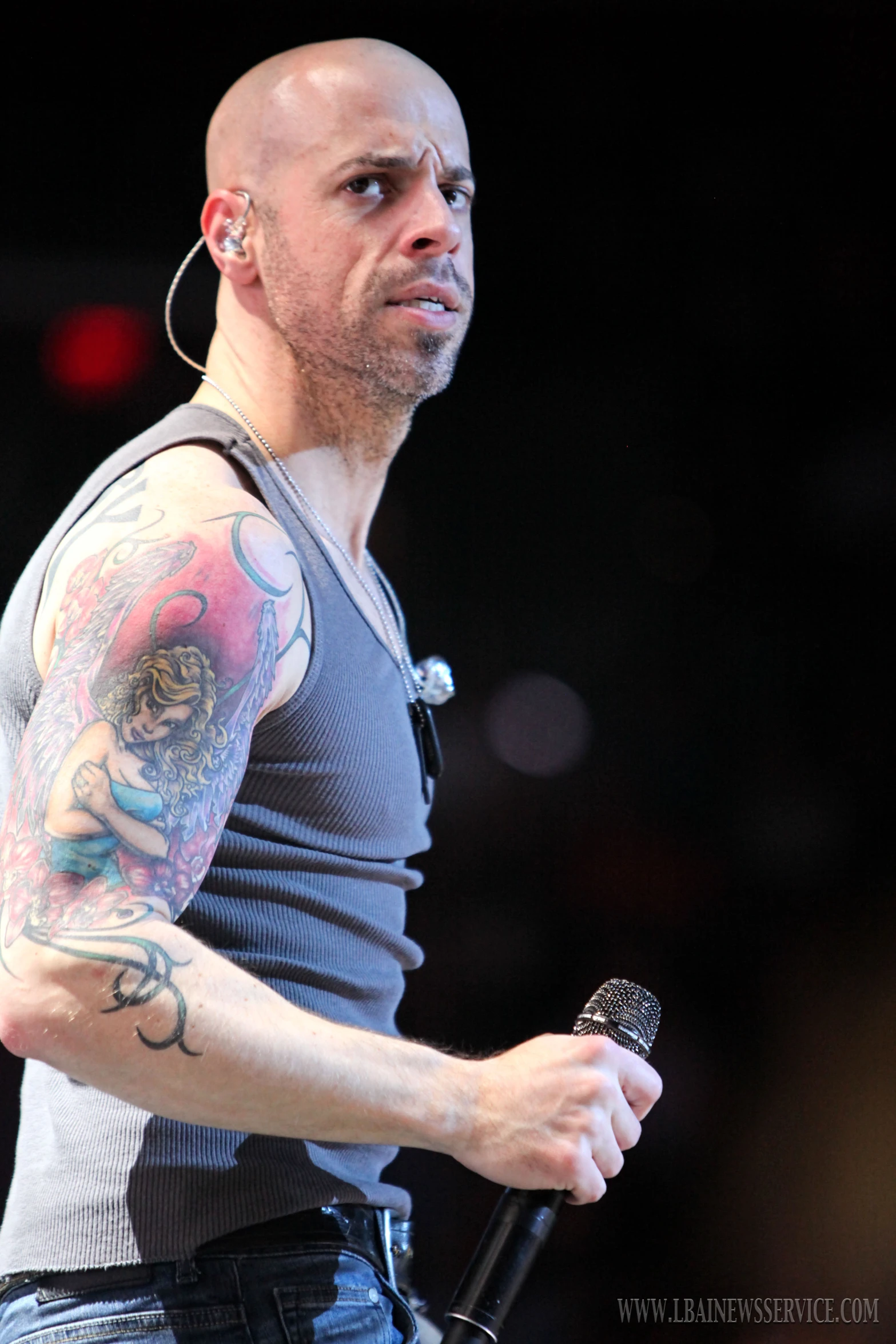 bald man with tattoos holding an microphone